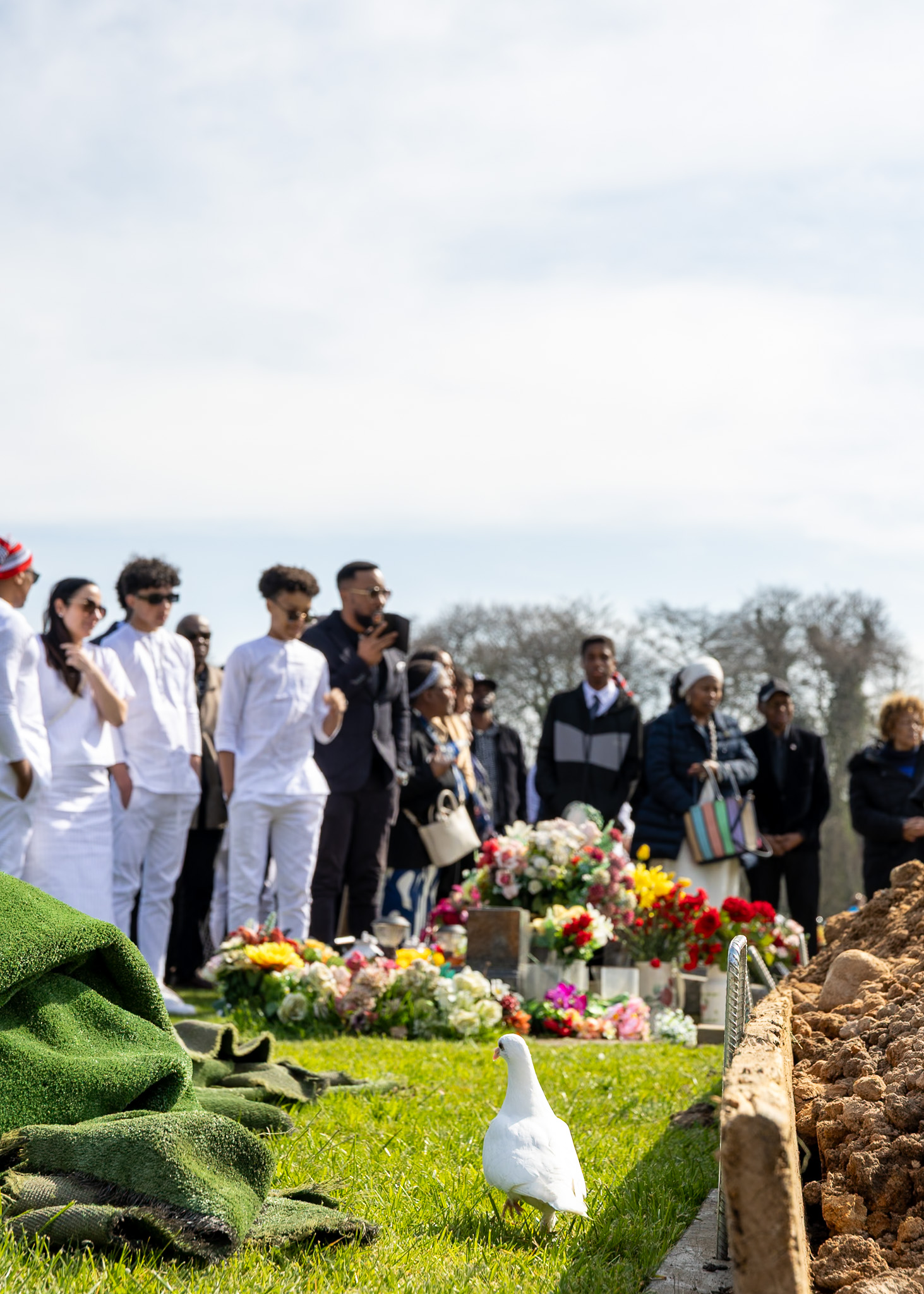 A burial service arranged by Memories Funeral Service, with mourners and floral tributes